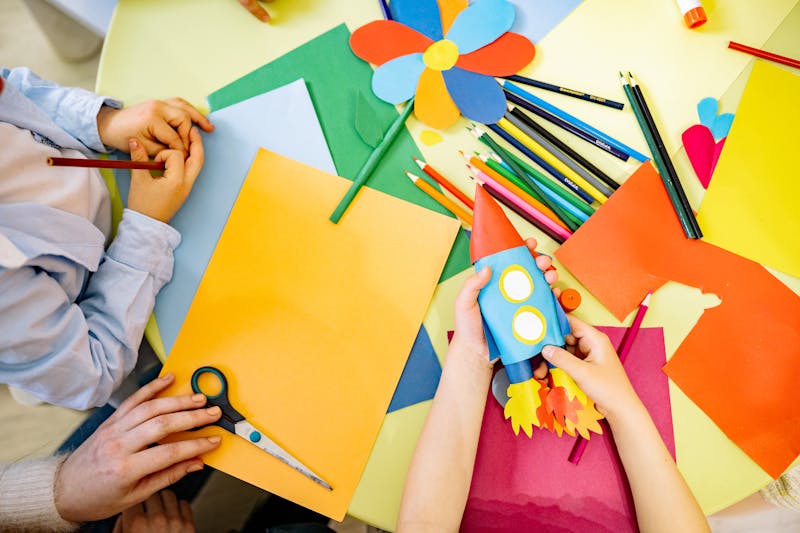 Kids doing arts and crafts with colorful paper at summer camp