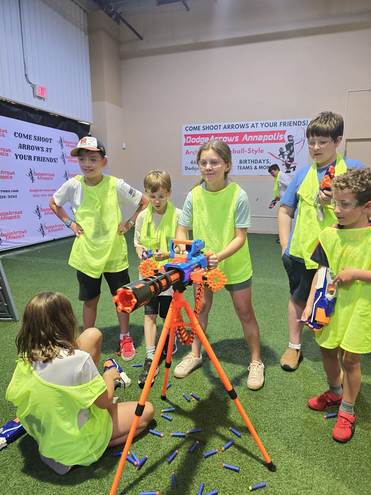 Child drawing a bow with a foam tipped arrow at archery tag