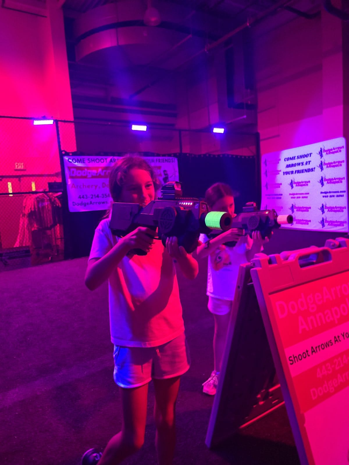 Kids playing laser tag with glow tape wrapped around the barrels under UV light